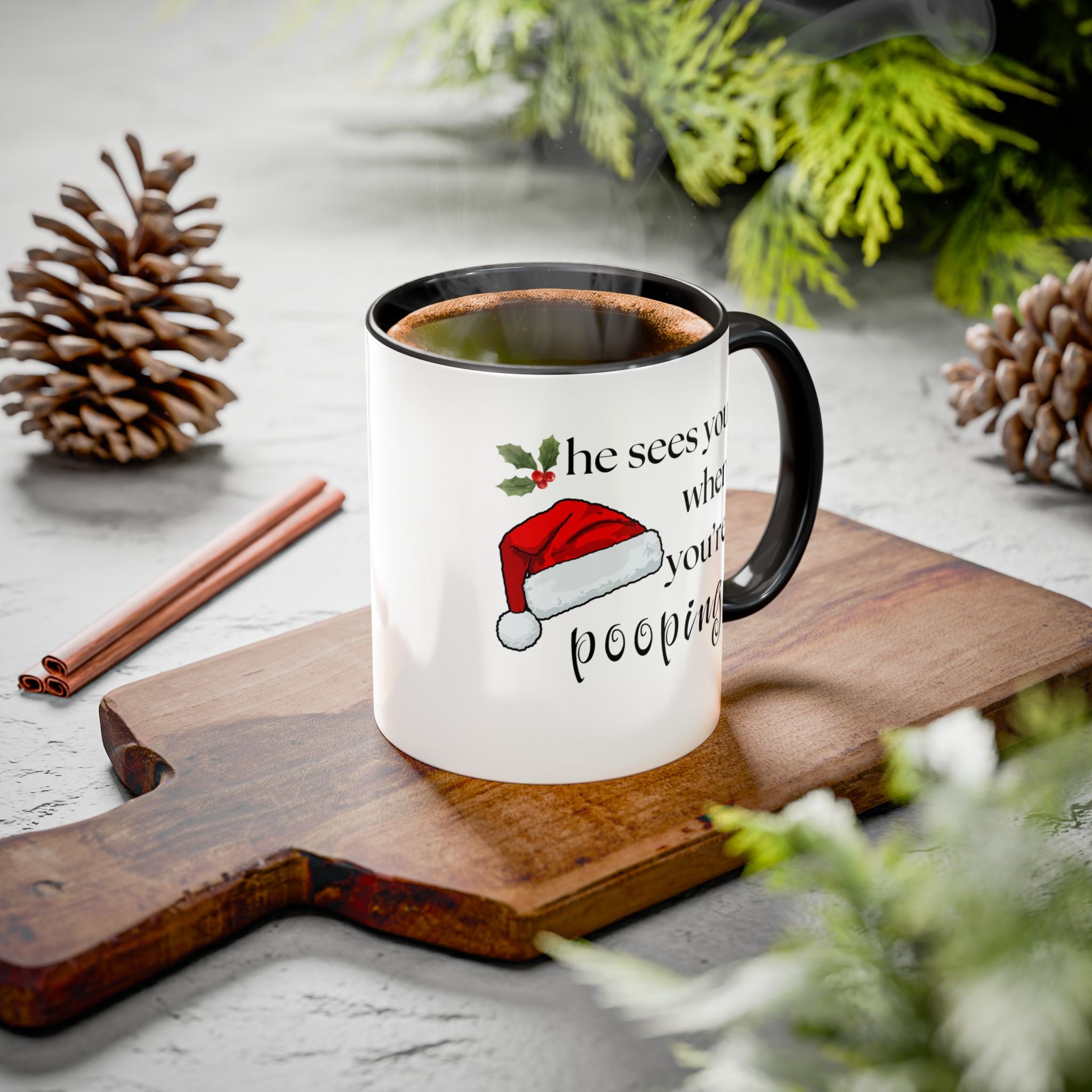 Mug with Christmas-themed text on a wooden board with pine cones and cinnamon sticks.
