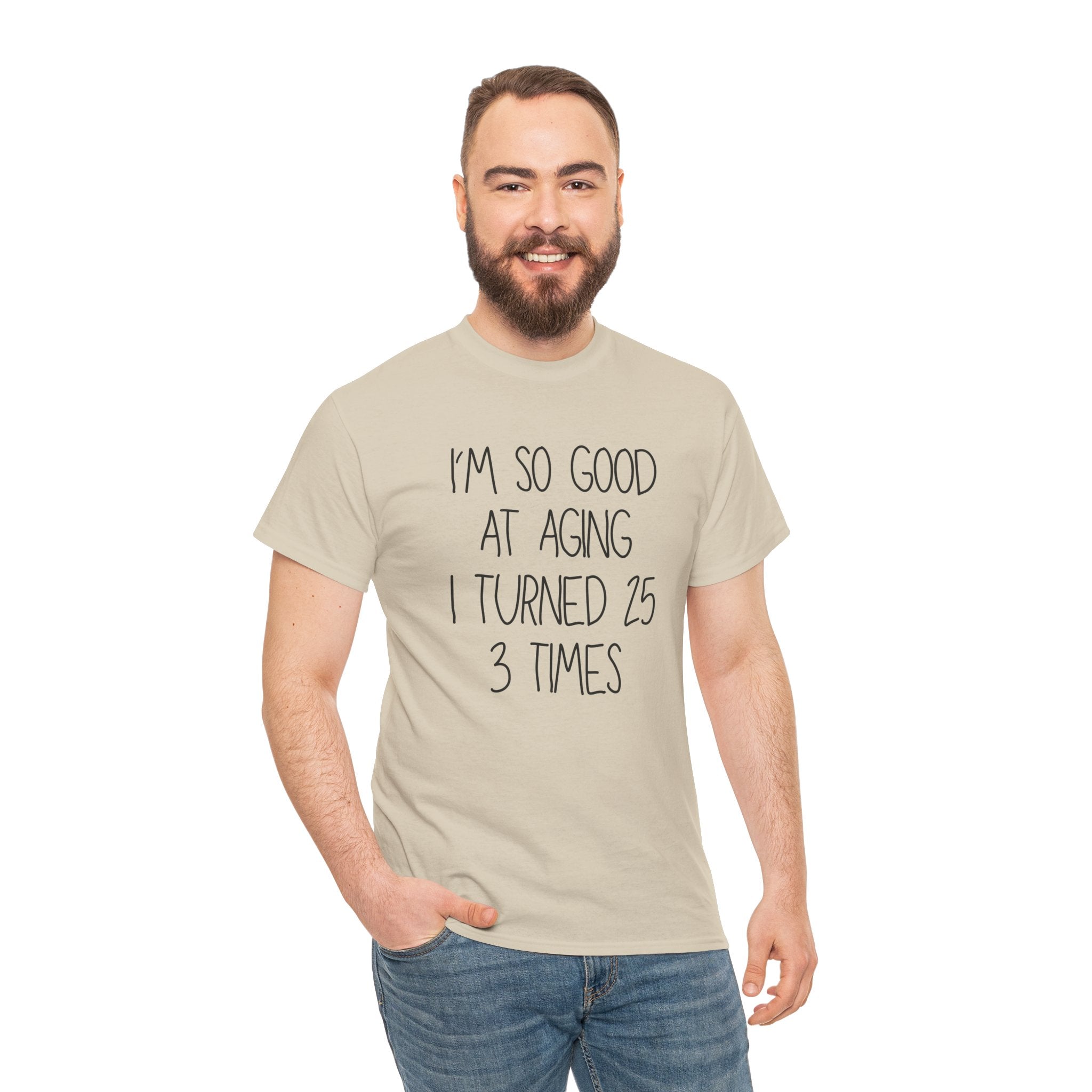 Man wearing a beige t-shirt with I'm So Good At Aging I Turned 25 3 Times text on a white background