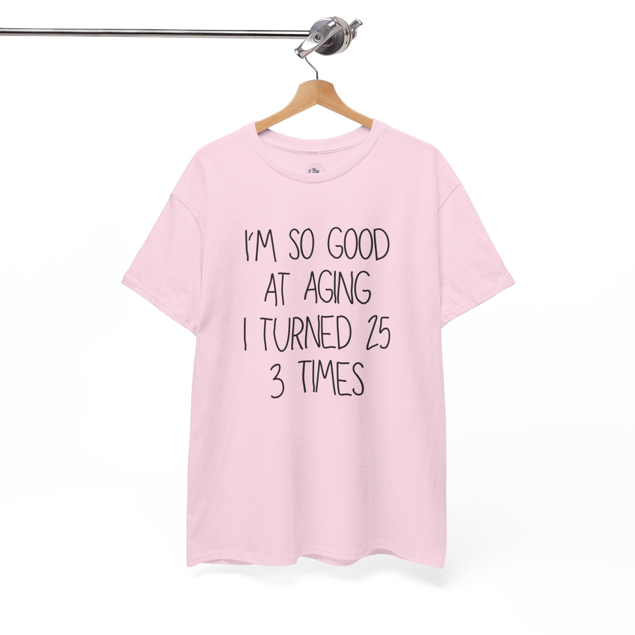 Pink t-shirt with humorous text on a hanger against a white background