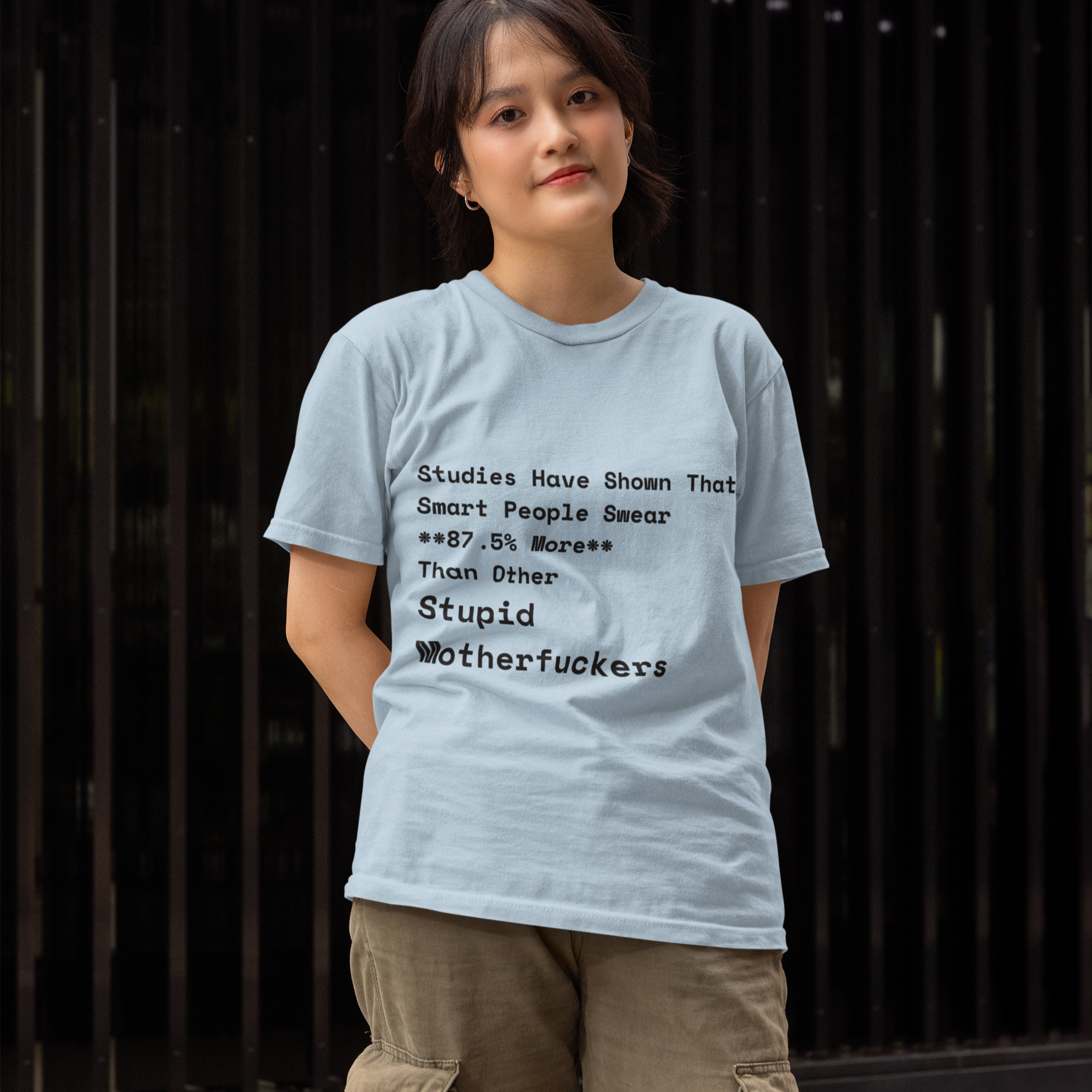 Person wearing a light blue t-shirt with text design against a dark background