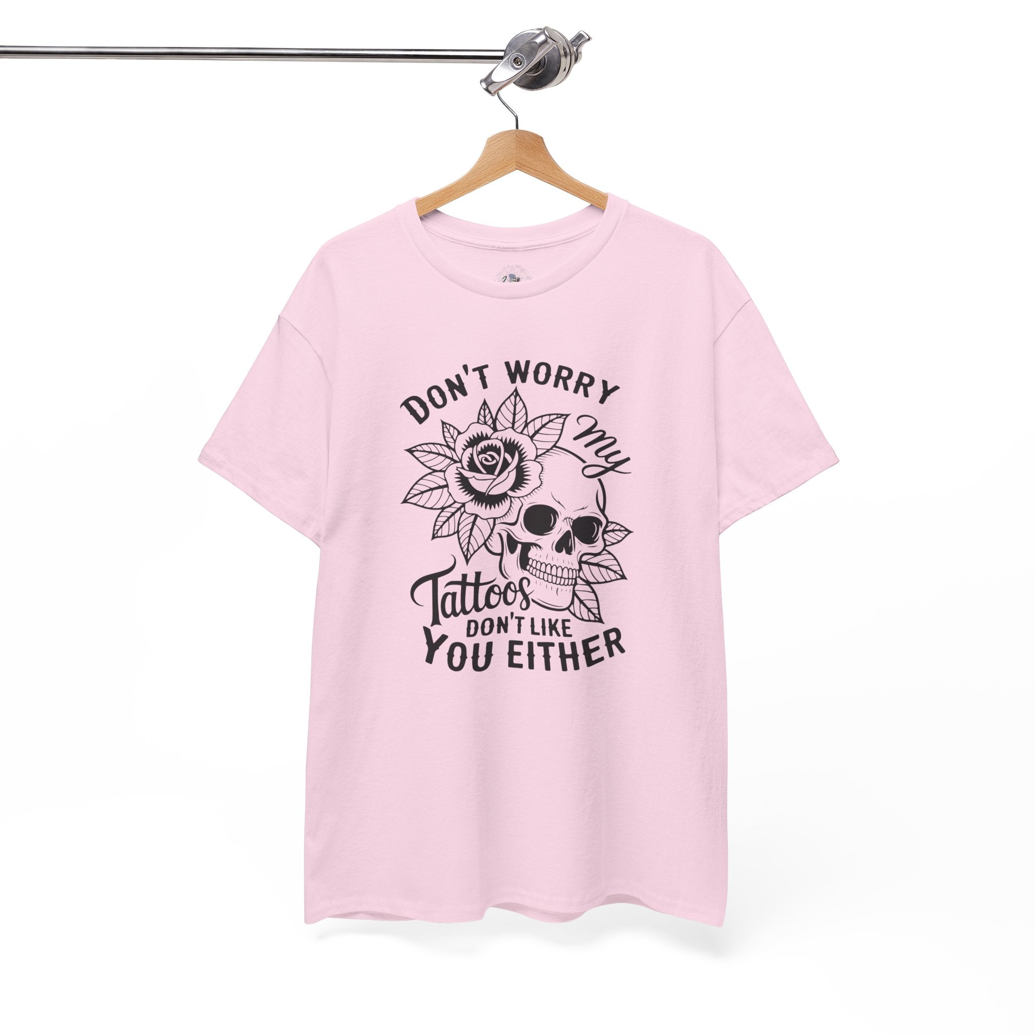 Pink t-shirt with skull and rose design and text on a hanger against a white background