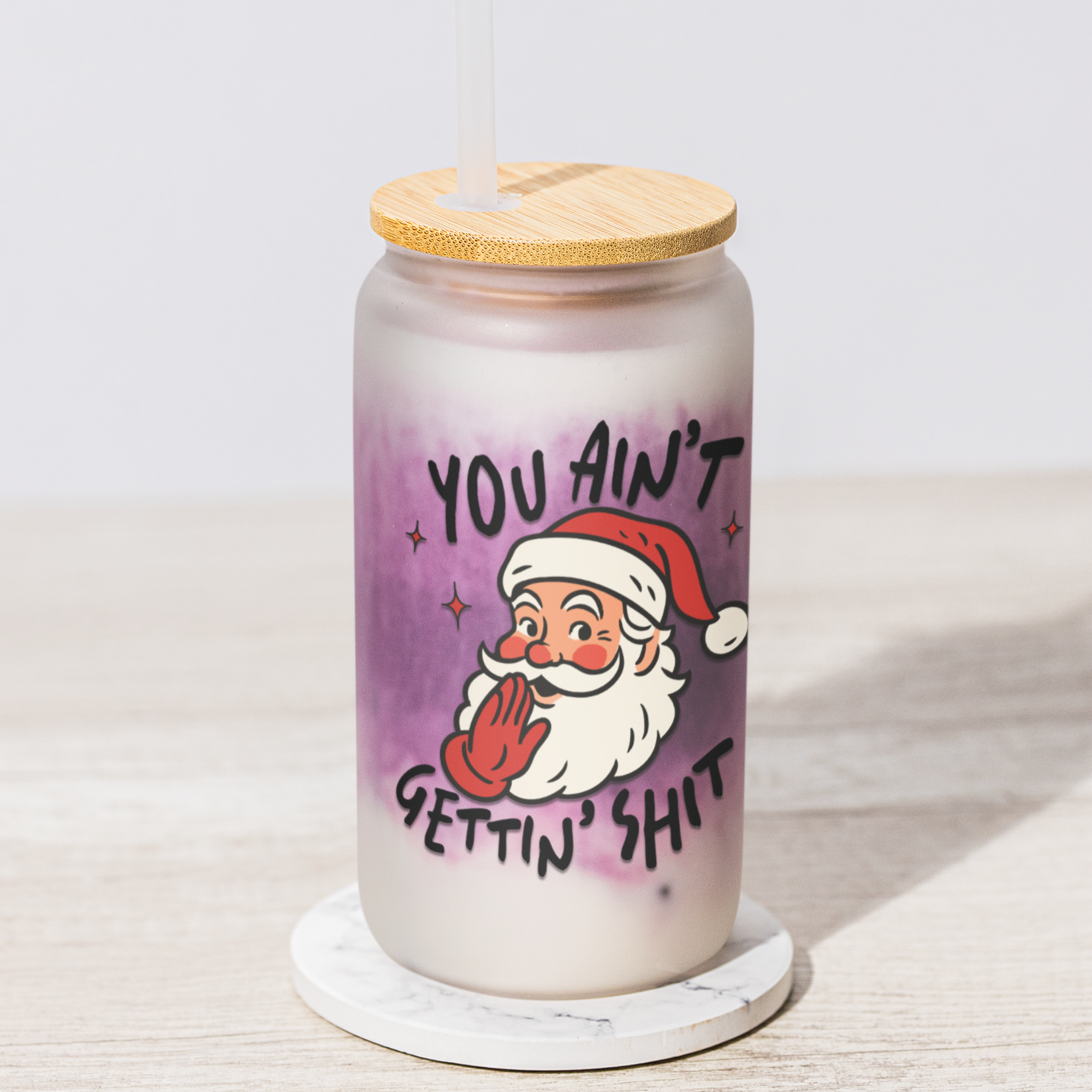 glass iced coffee mug with a wooden lid featuring a cartoon Santa Claus and text on a white background.