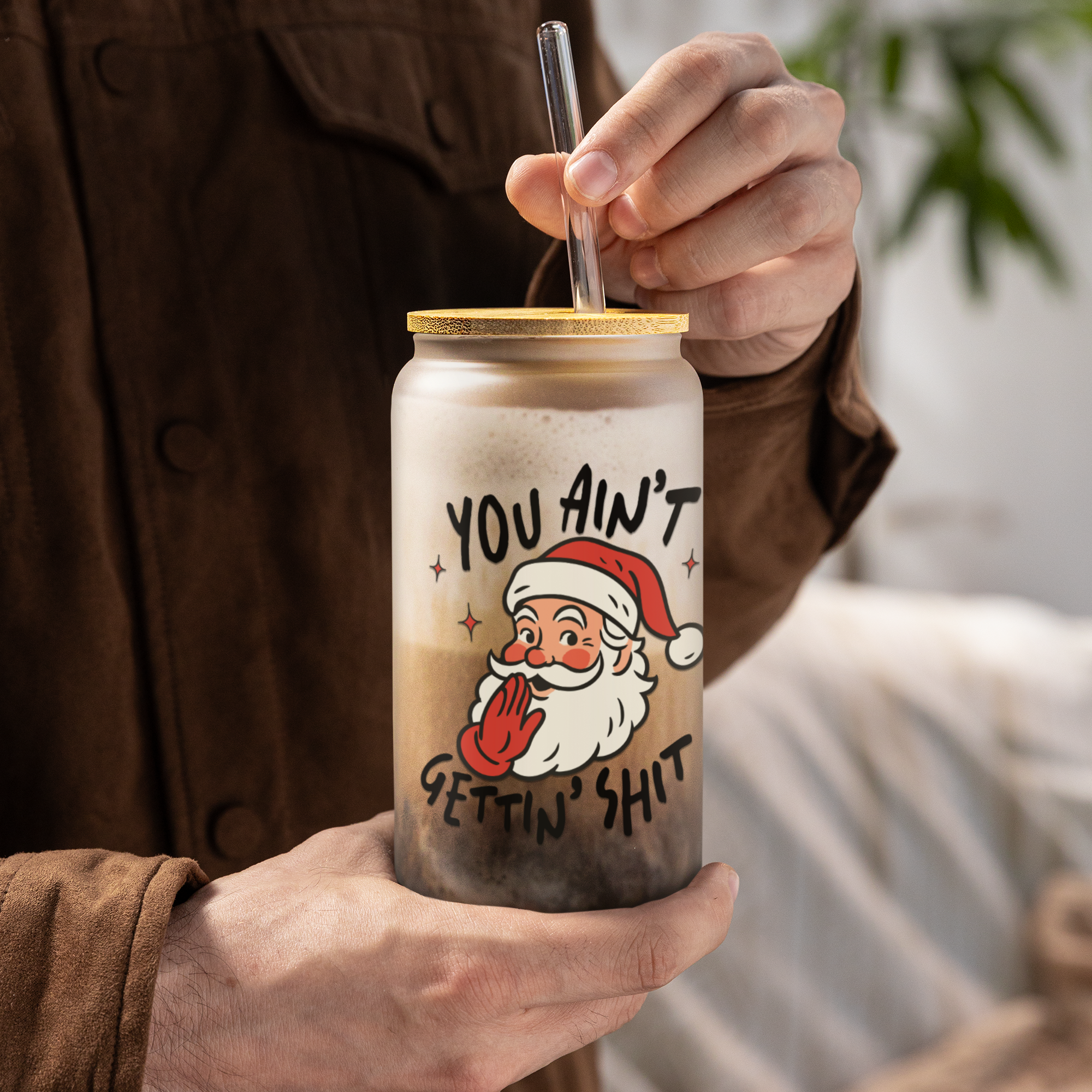 Person holding a jar with a humorous Santa Claus design and text.