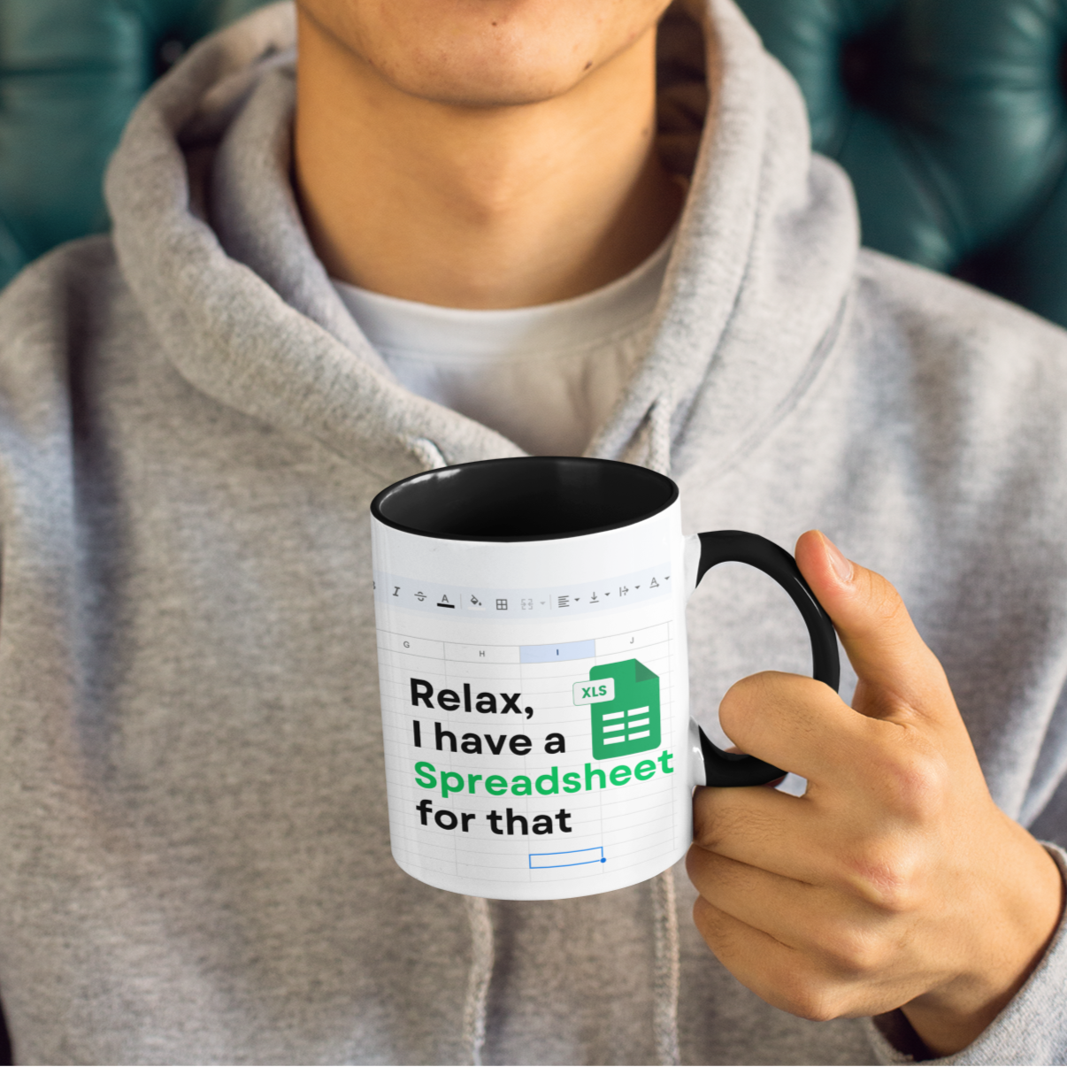Person holding a mug with text, sitting on a green leather couch