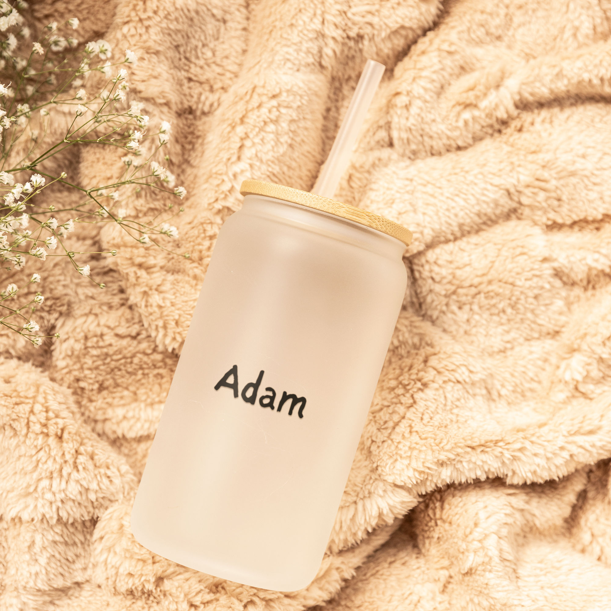 Tumbler with personalized name on a soft, beige blanket.