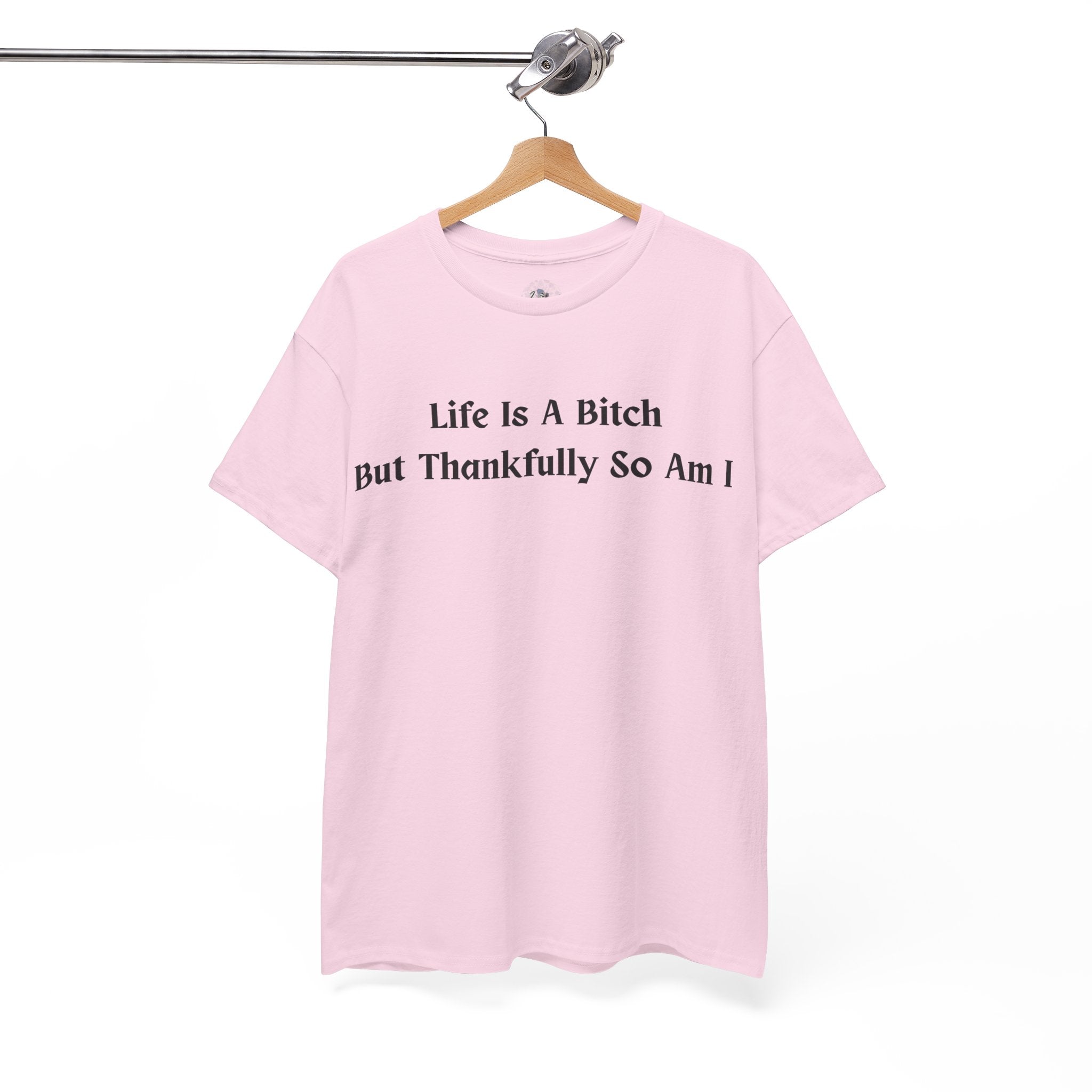 Pink t-shirt with black Life Is A Bitch But Thankfully So Am I text on a hanger against a white background