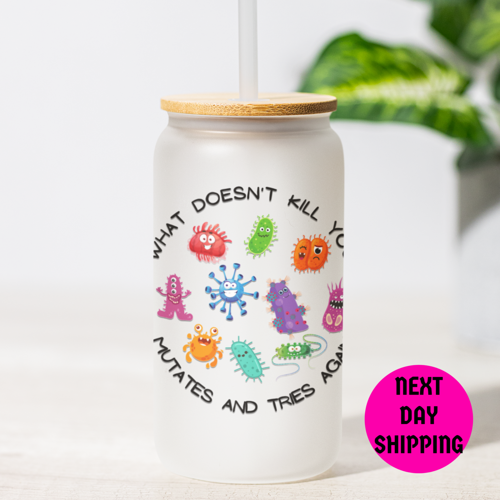 Frosted tumbler with colorful virus illustrations and What Doesn't Kill You Mutates and Tries Again text on a white background with a plant in the background
