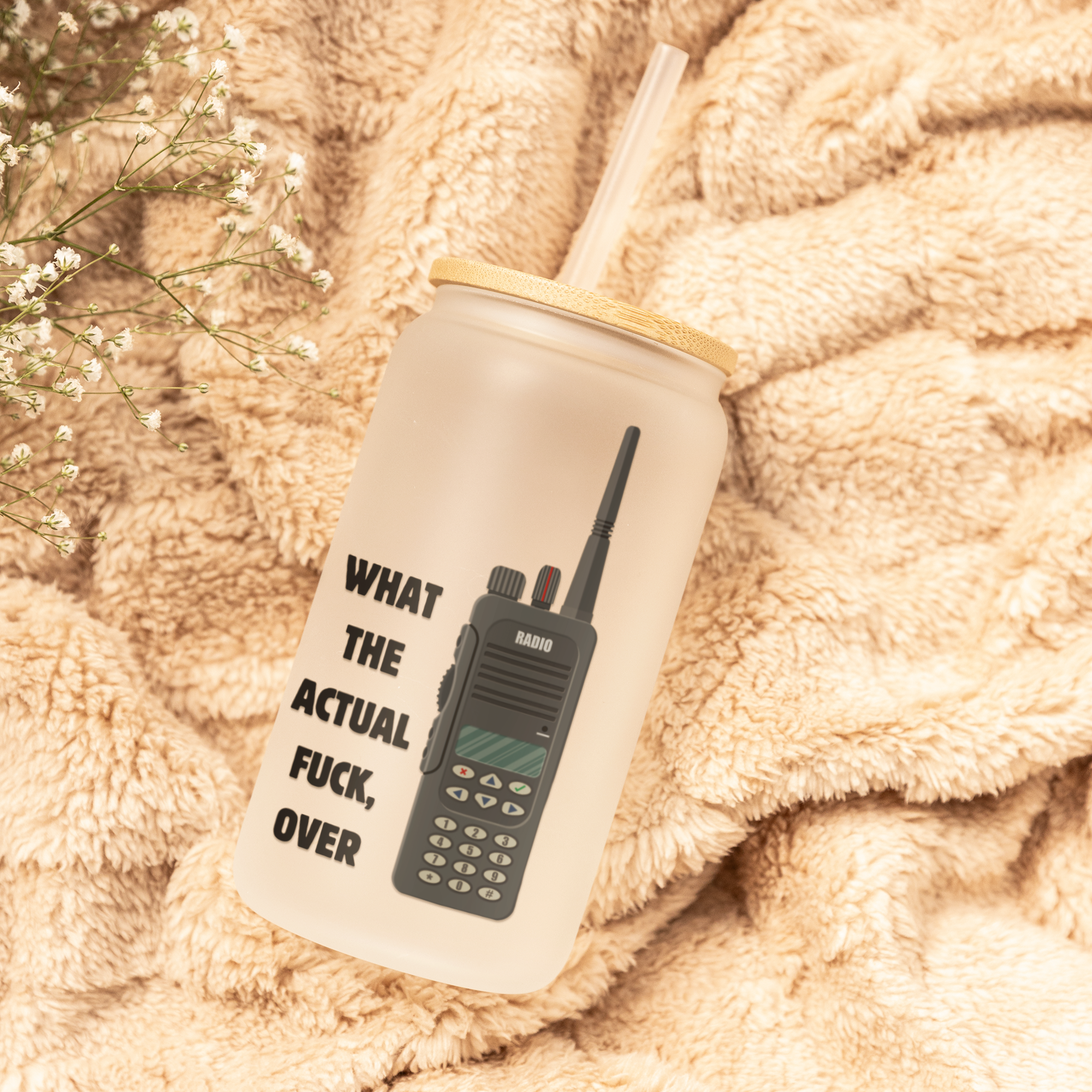 Tumbler with 'What The Actual Fuck Over' text on a soft beige blanket