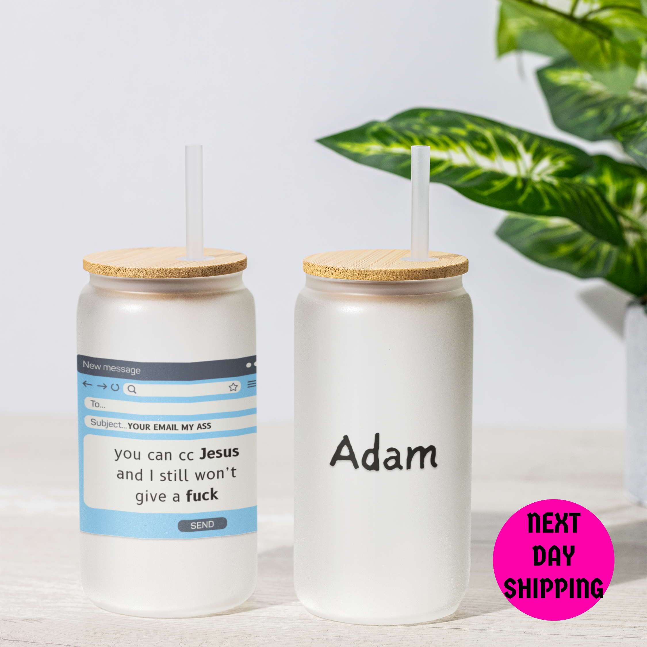 Two clear tumblers with wooden lids and printed text on a light surface with a plant in the background.